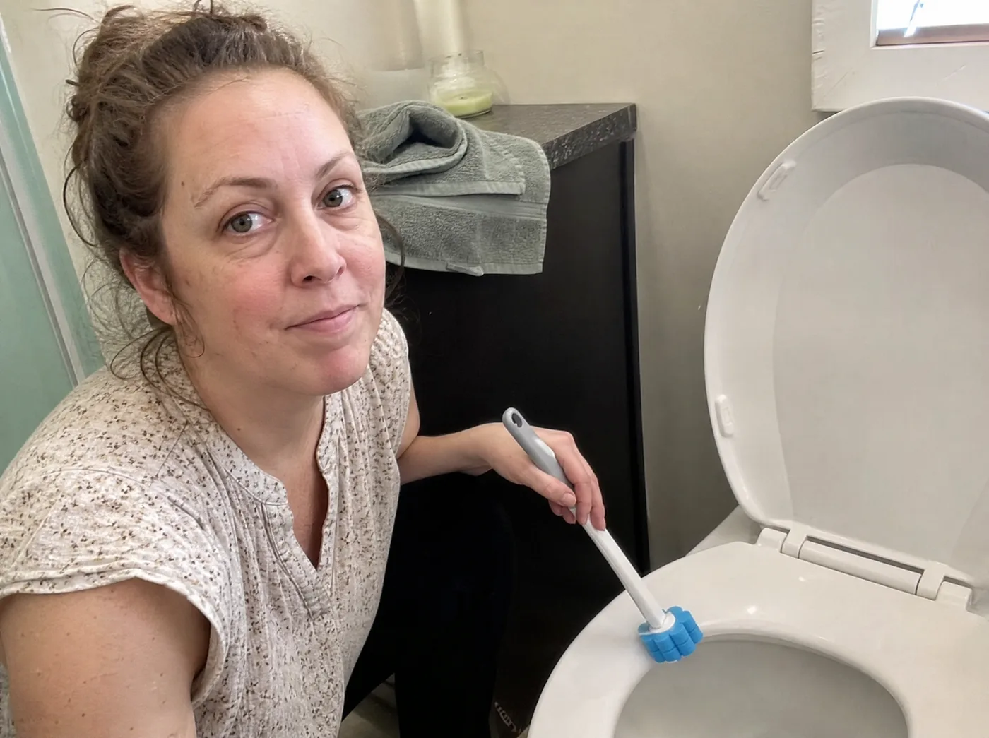 Woman cleaning a guest toilet with the TossClean wand before visitors arrive