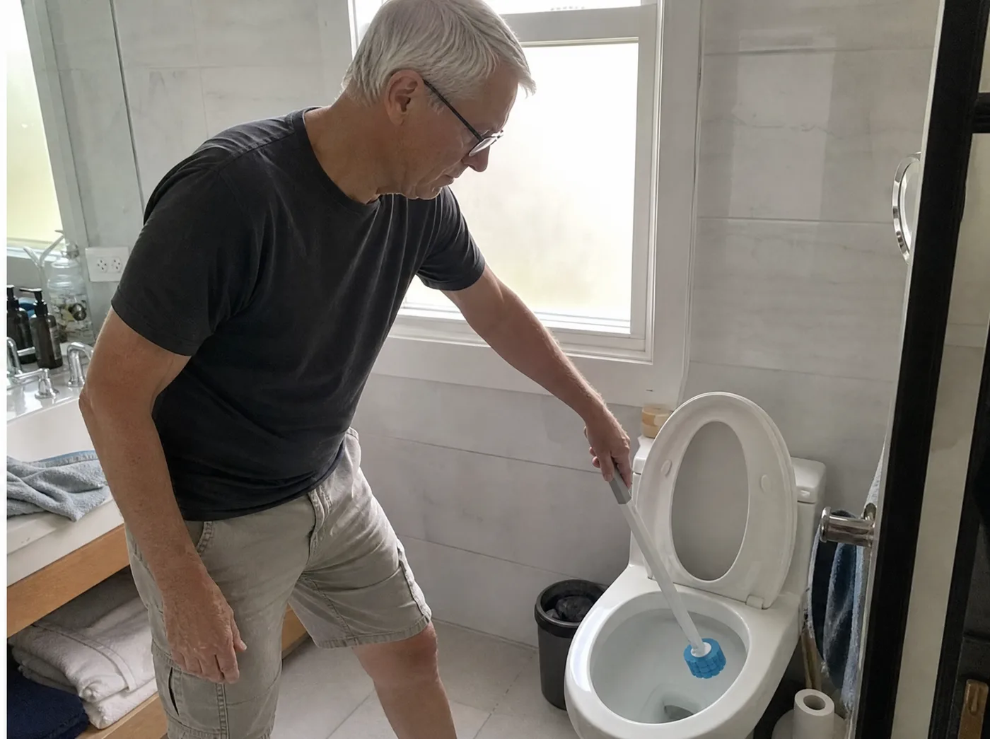 Older man cleaning the toilet standing upright with the long TossClean wand